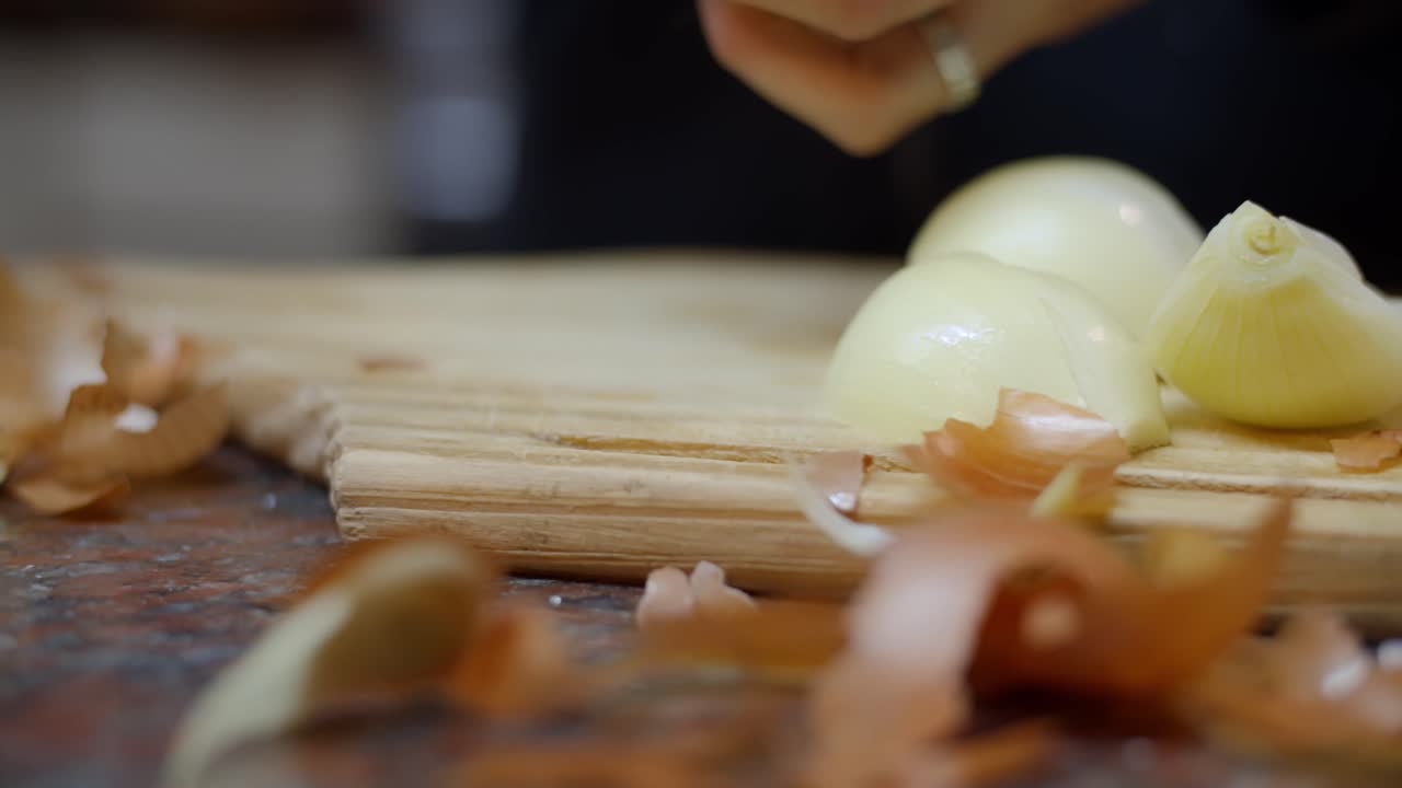 Woman's hands cutting an onion at home with painted nails - Warm house vibes - cooking at home - 4k at 60fps (slowmotion)