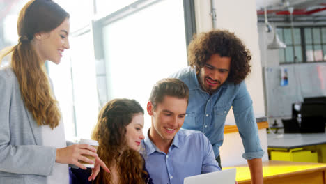 Business-executives-discussing-over-laptop-in-meeting