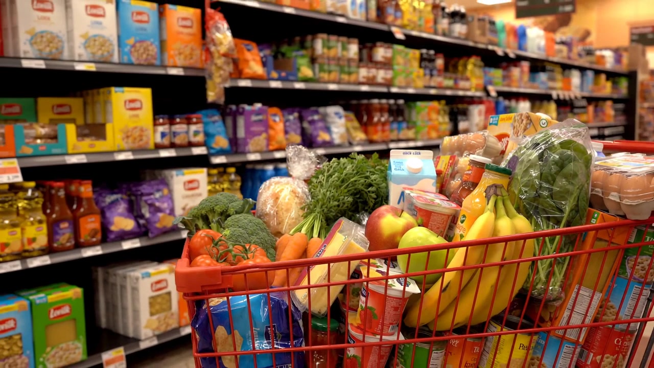 Cesto della spesa pieno di prodotti alimentari freschi nel corridoio del supermercato che rappresenta lo shopping dei consumatori e la spesa domestica nella vita quotidiana catturata in