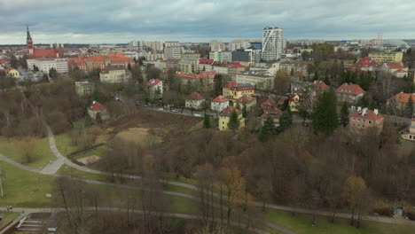 Aerial-view-of-Olsztyn's-old-town,-historical-architecture,-spires,-red-roofs,-modern-skyline,-urban-greenery,-development-contrast