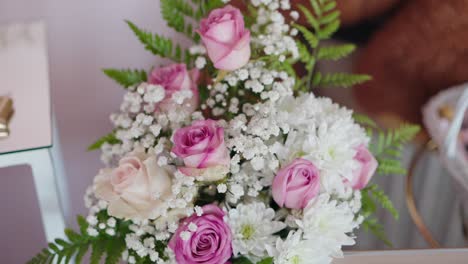 close up of a floral arrangement with pink roses white daisies baby's breath and green ferns