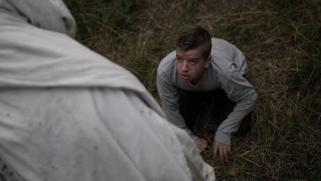 Crying teenage boy looks up at robed man