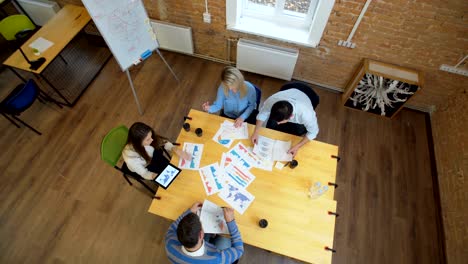 reunión de negocios en el loft espacio compartido. equipo hablando, mujer gerente dando dirección a la gente. vista superior.