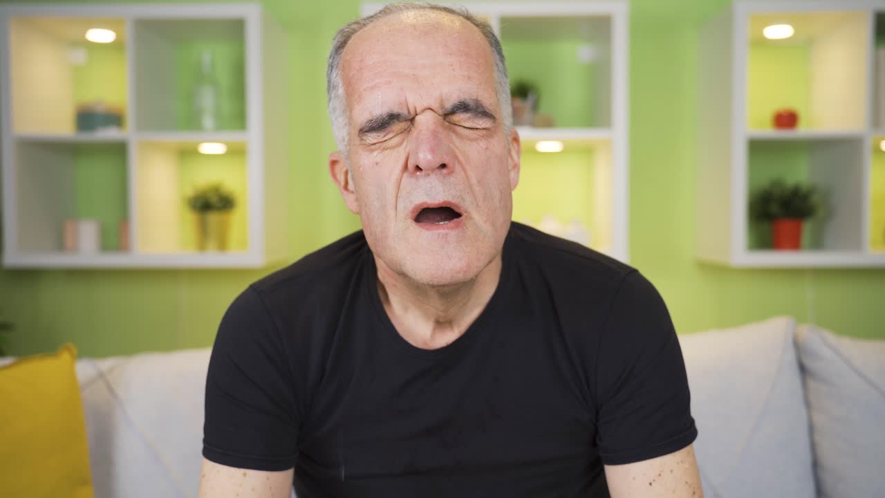 el anciano que está cansado de sudar, se limpia el sudor con la mano y está abrumado.