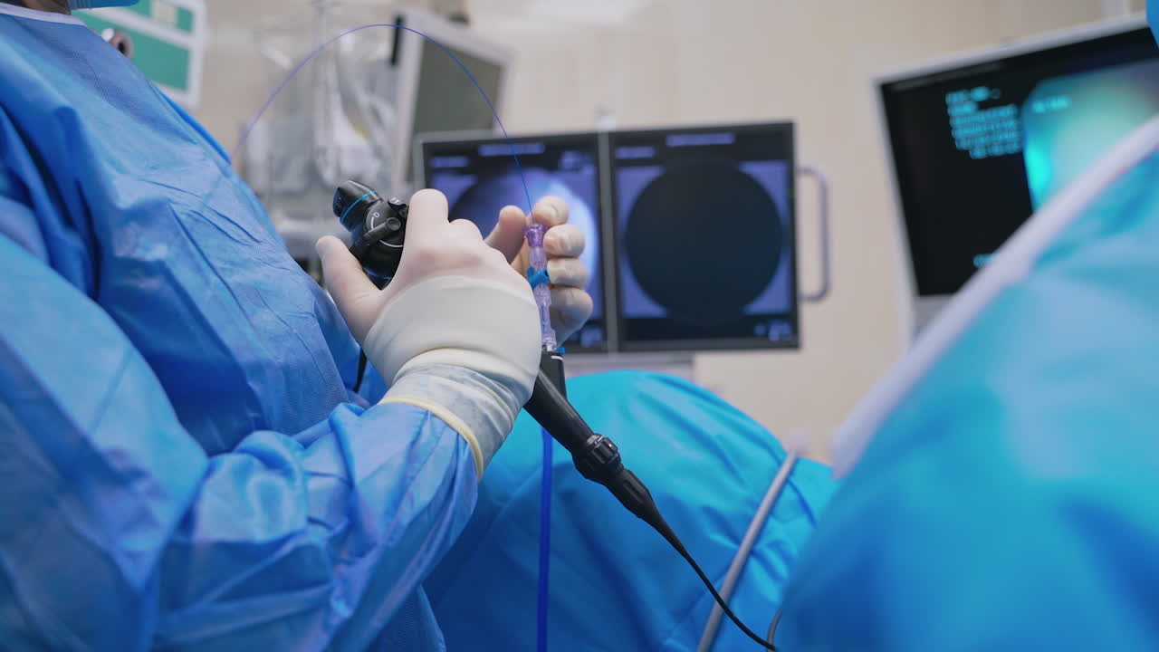 Doctor uses innovative equipment in operating room. Surgeon holds modern instrument on monitors background in clinic. Modern technologies in medicine.