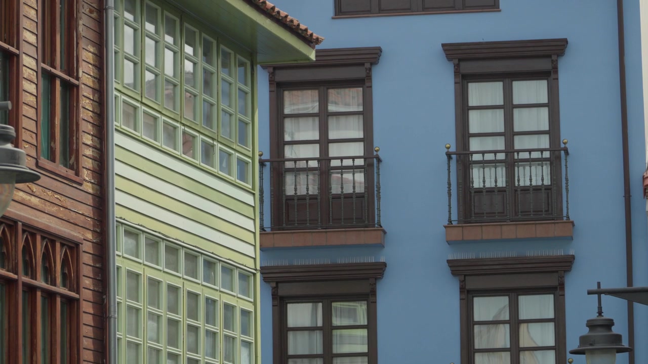 Primo piano ravvicinato di finestre tradizionali in legno bianco e balcone su facciata di edificio colorato
