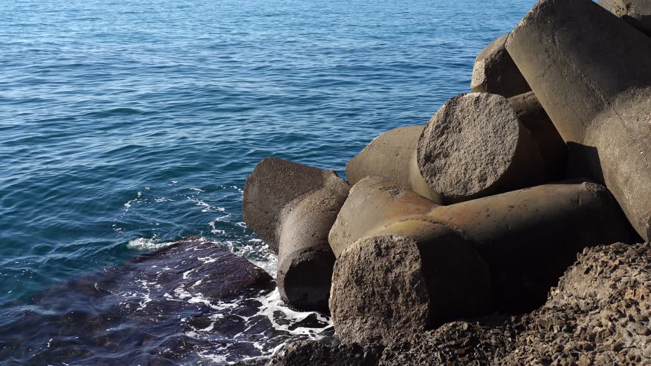 Rough water waves breaking sea shore and crashing, powerful natural sea phenomenon. Stone blocks defending sea pier from flood, massive rocks fortification of the sea beach