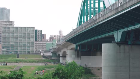 marukobashi bridge over the tamagawa river with japanese kids playing soccer on the foreground in tokyo, japan