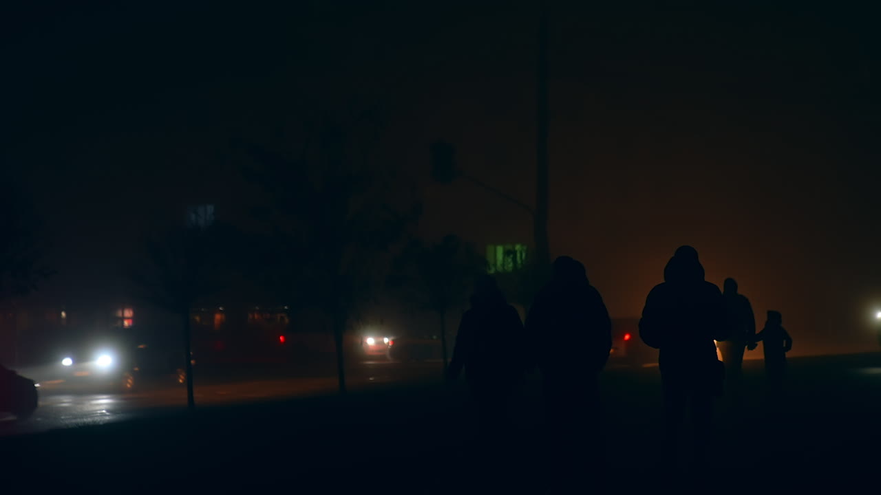 People Walking at Night in Foggy City Street