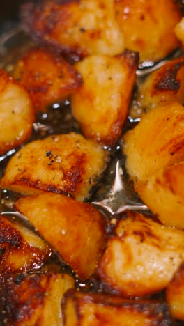 vertical video of freshly roasted golden potatoes bubbling in hot olive oil. crispy delicious british food ready to eat.