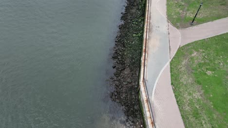 A-top-down-view-of-the-East-River-near-a-park-in-Queens,-NY-on-a-cloudy-day