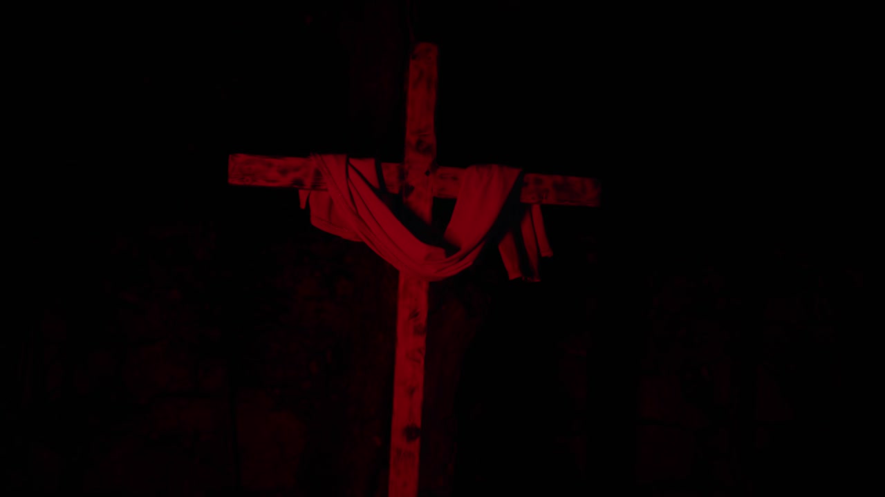 Wooden cross with cloth illuminated by changing lights at night