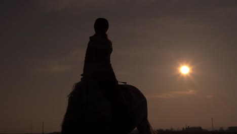 Silueta-De-Jinete-Sentado-A-Caballo-En-Una-Espectacular-Puesta-De-Sol,-ángulo-Bajo