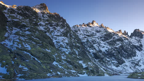 puesta de sol en la laguna grande de gredos, reflejo perfecto de las montañas en el lago medio congelado