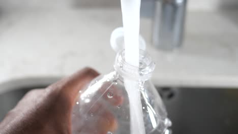 filling a plastic water bottle from a kitchen tap