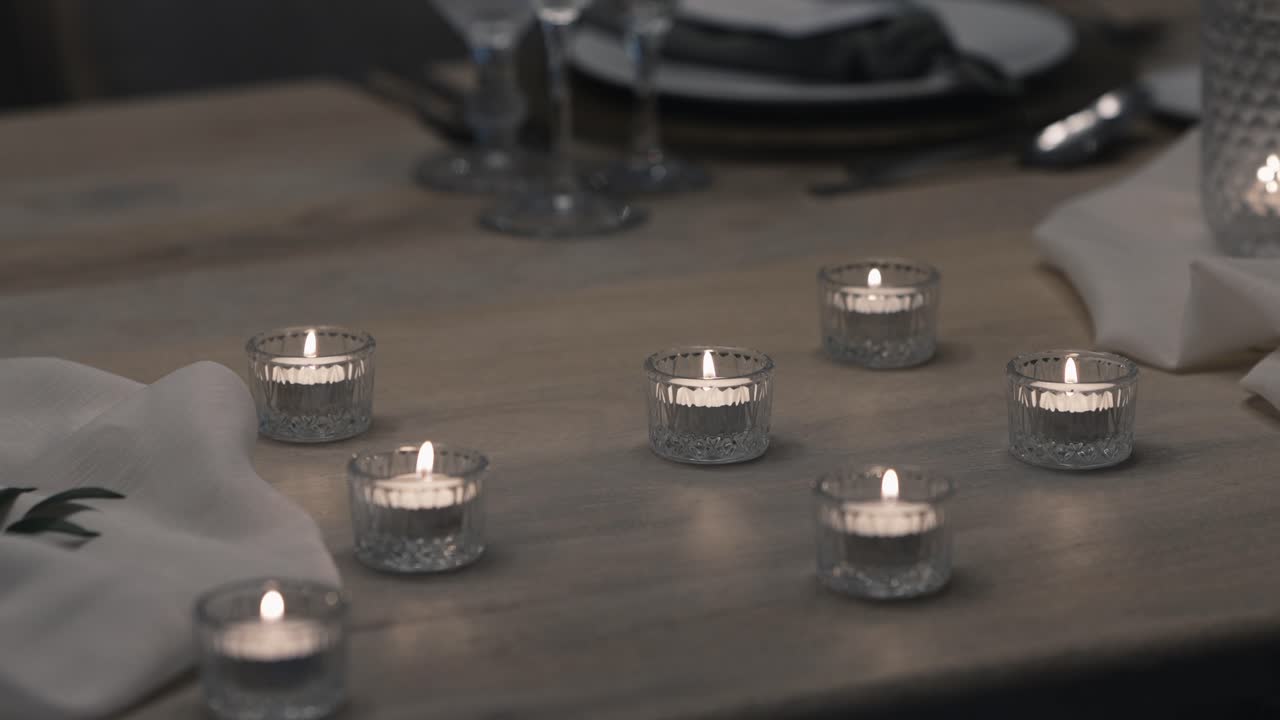 velas en soportes de vidrio dispuestos en una mesa de madera para una elegante configuración de cena