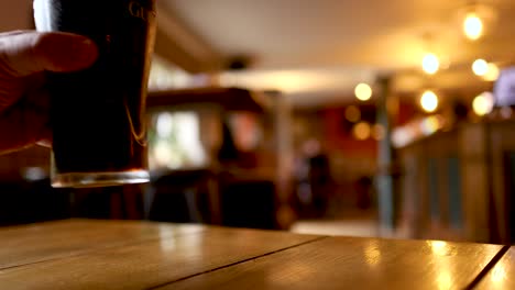 a hand grabs a pint of stout