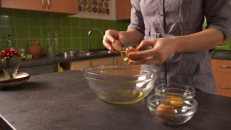 primer plano de una mujer joven rompiendo huevos y separando la yema y la clara de huevo en tazones de vidrio