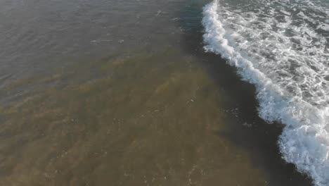 drone flying towards tropical water at hiriketiya beach in sri lanka