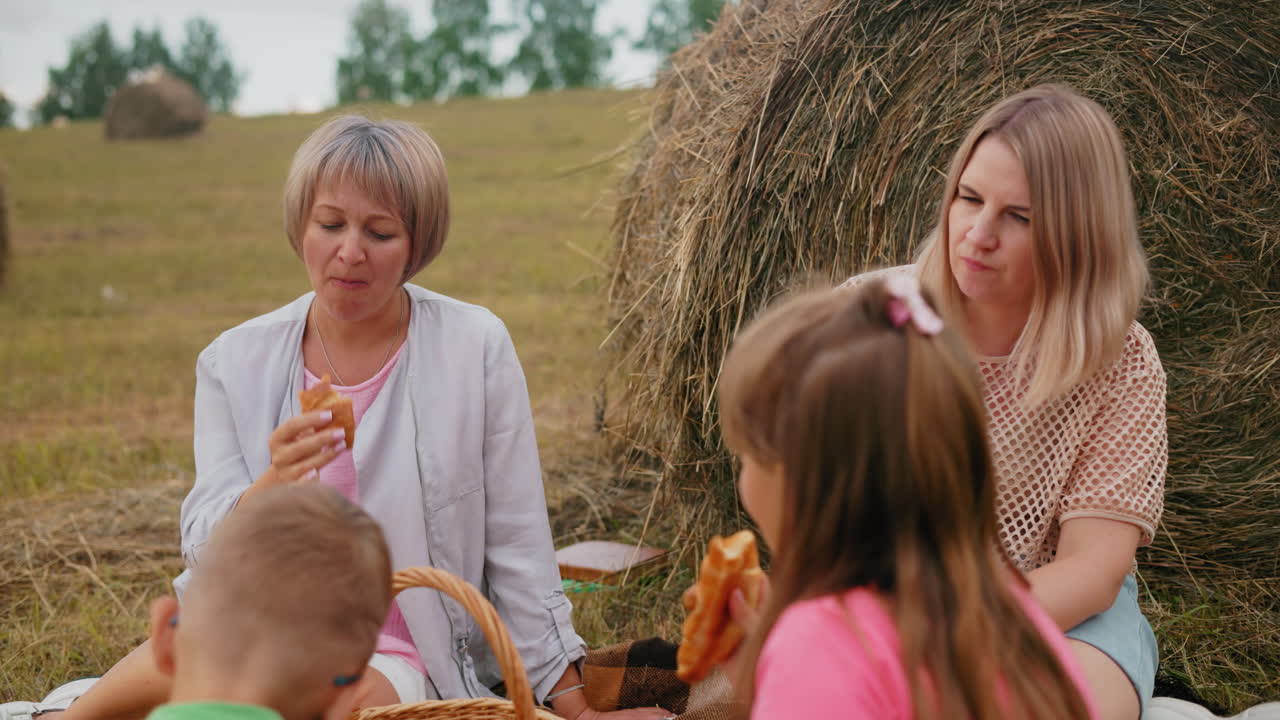 밖에서 앉아있는 두 아이의 뒷면, 어머니가 조용히 물고기 롤을 는 동안, 그녀의 이모는 평화로운 야외에서 그들의 에 피크닉 바구니를 가지고 즐기고 있습니다.