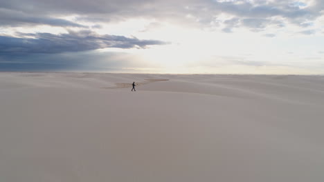 Antena-De-4k-De-Silueta-De-Hombre-Caminando-Sobre-Hermosas-Dunas-De-Arena-Blanca-Al-Amanecer