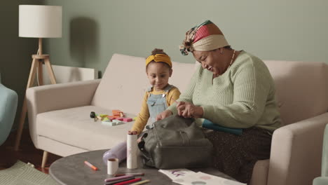 grandmother helping her granddaughter packing school bag