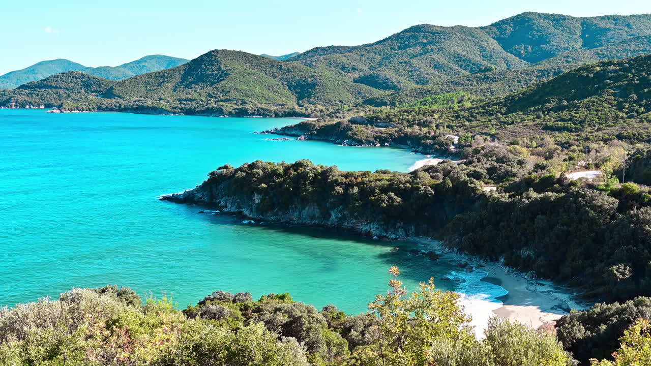 Costa del Mar Egeo con acqua blu trasparente, vegetazione intorno, rocce, cespugli e alberi, vista dal fuco, Grecia
