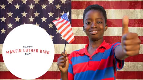 Animation-of-happy-martin-luther-king-day-text-over-happy-african-american-boy-with-american-flag