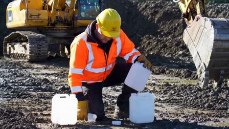 construction worker taking water or soil samples on a muddy site
