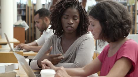 Closeup-shot-of-focused-women-using-laptop-at-library