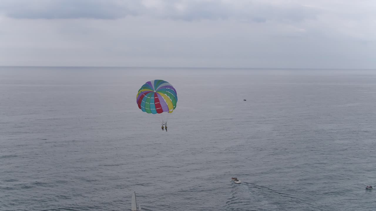 una vista panorámica de personas haciendo parasailing sobre un hermoso océano en calma en un día nublado