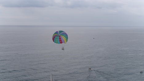 Una-Vista-Panorámica-De-Personas-Haciendo-Parasailing-Sobre-Un-Hermoso-Océano-En-Calma-En-Un-Día-Nublado