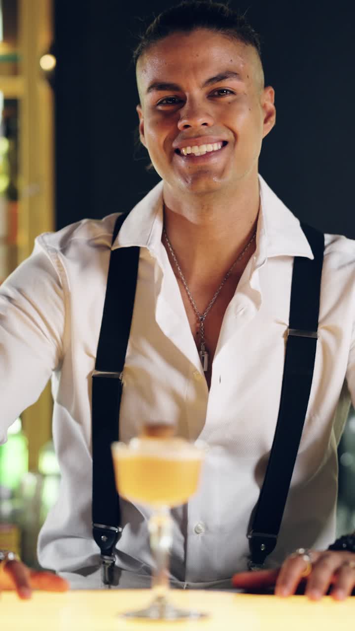 Lächelnder Barkeeper blickt von seinem Cocktail an der Bar auf.