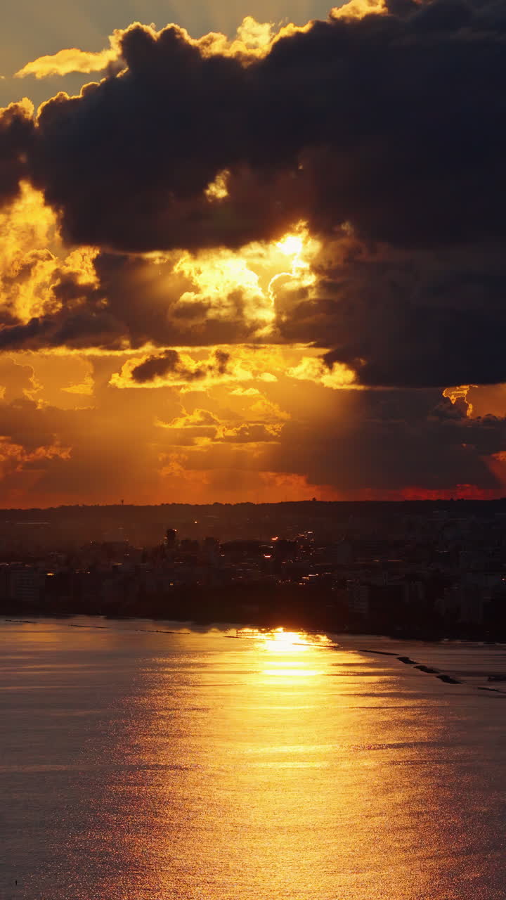 Drohnenaufnahme über der Skyline von Limassol mit leuchtendem Horizont und Silhouetten urbaner Strukturen. Vertikal.