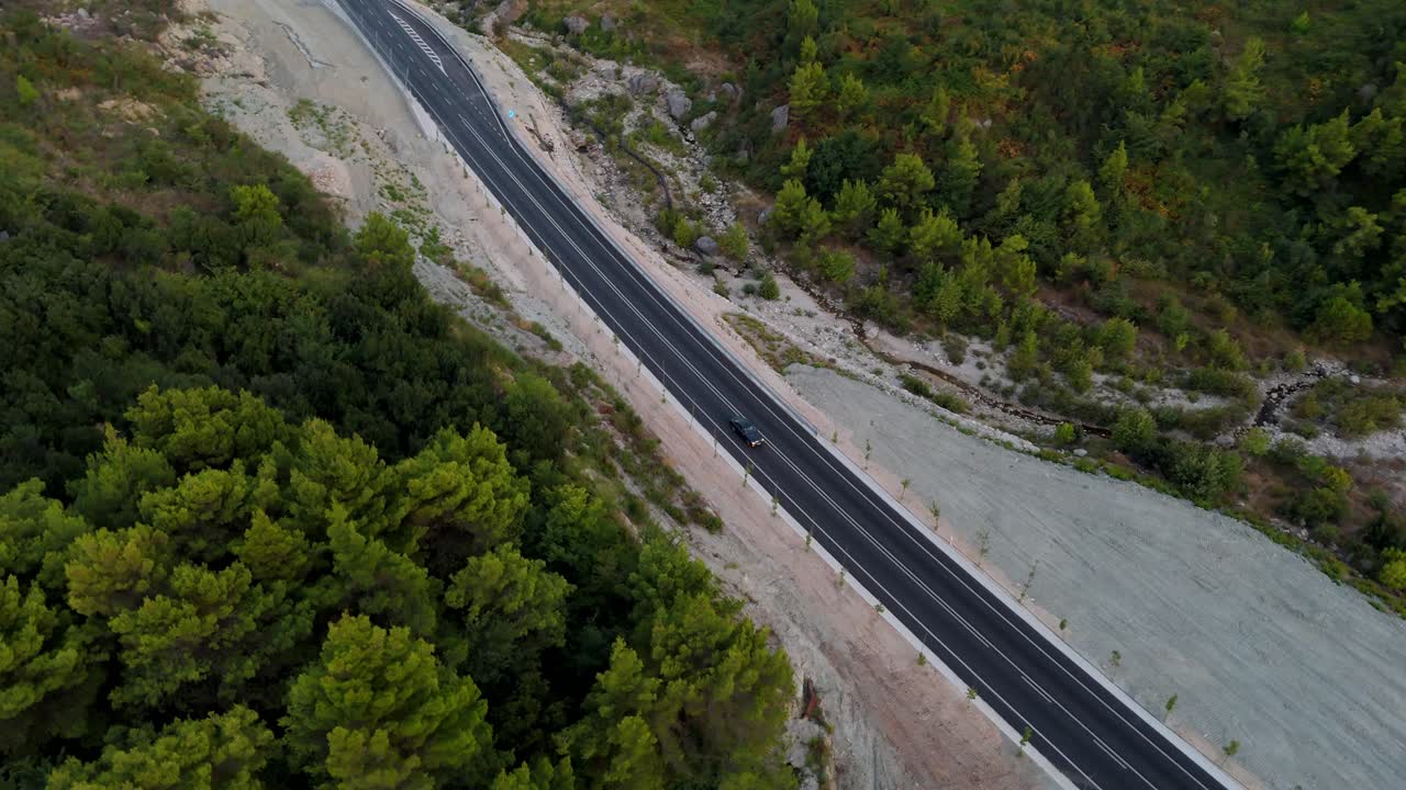 un camino sinuoso que atraviesa un exuberante paisaje forestal al amanecer, vista aérea