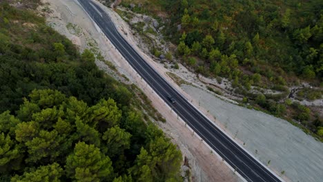 un camino sinuoso que atraviesa un exuberante paisaje forestal al amanecer, vista aérea