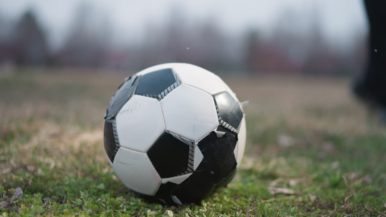 Blurred view of someone playing football on a grassy field with a football goal post visible in the background