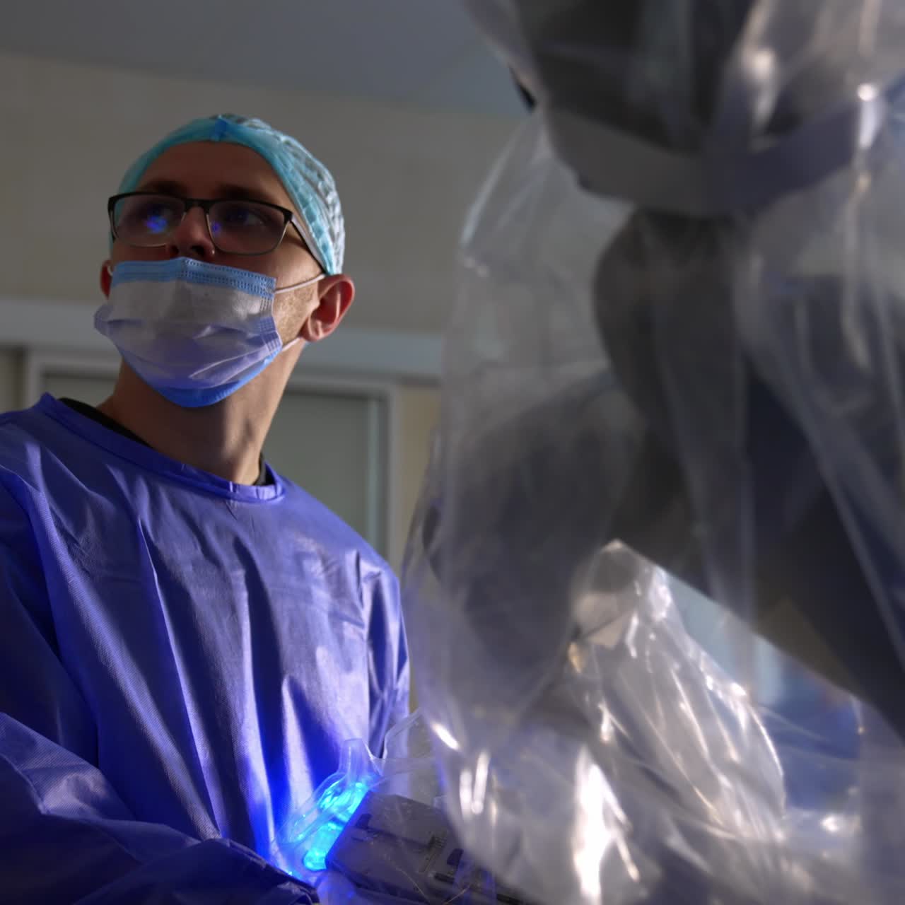 Confident focused medical specialist at work. Male young adult surgeon watches the operational procedure conducted by Da Vinci robot