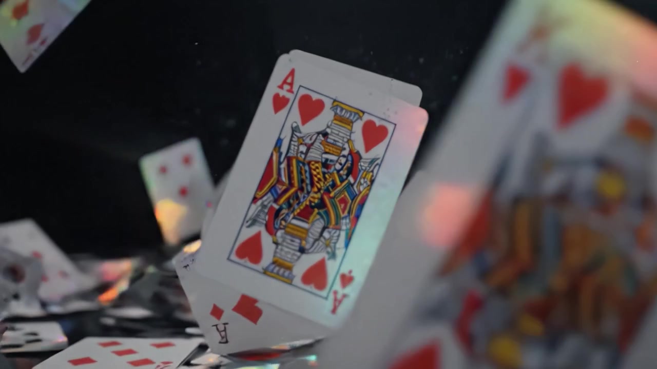 Esplosione dinamica di carte da gioco: immagini accattivanti di carte che cadono e si spargono su uno sfondo scuro, mostrando movimento e riflessi di luce