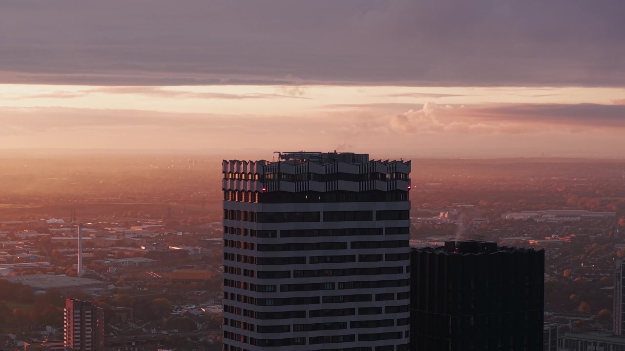 Vista aerea in parallasse di Croydon, con lo skyline di grattacieli sotto un tramonto dorato e velato.