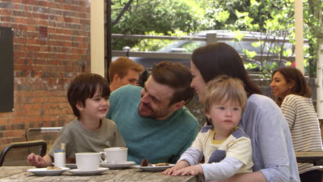 la familia se sienta en la mesa de la cafetería al aire libre con un bocadillo en r3d
