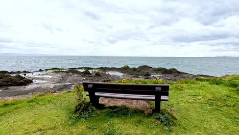 bench facing the sea with rocky coastline