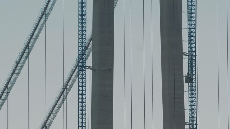 Static close up shot of an elevator going up to the top of a suspended bridge under construction, big structure