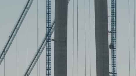 Static-close-up-shot-of-an-elevator-going-up-to-the-top-of-a-suspended-bridge-under-construction,-big-structure