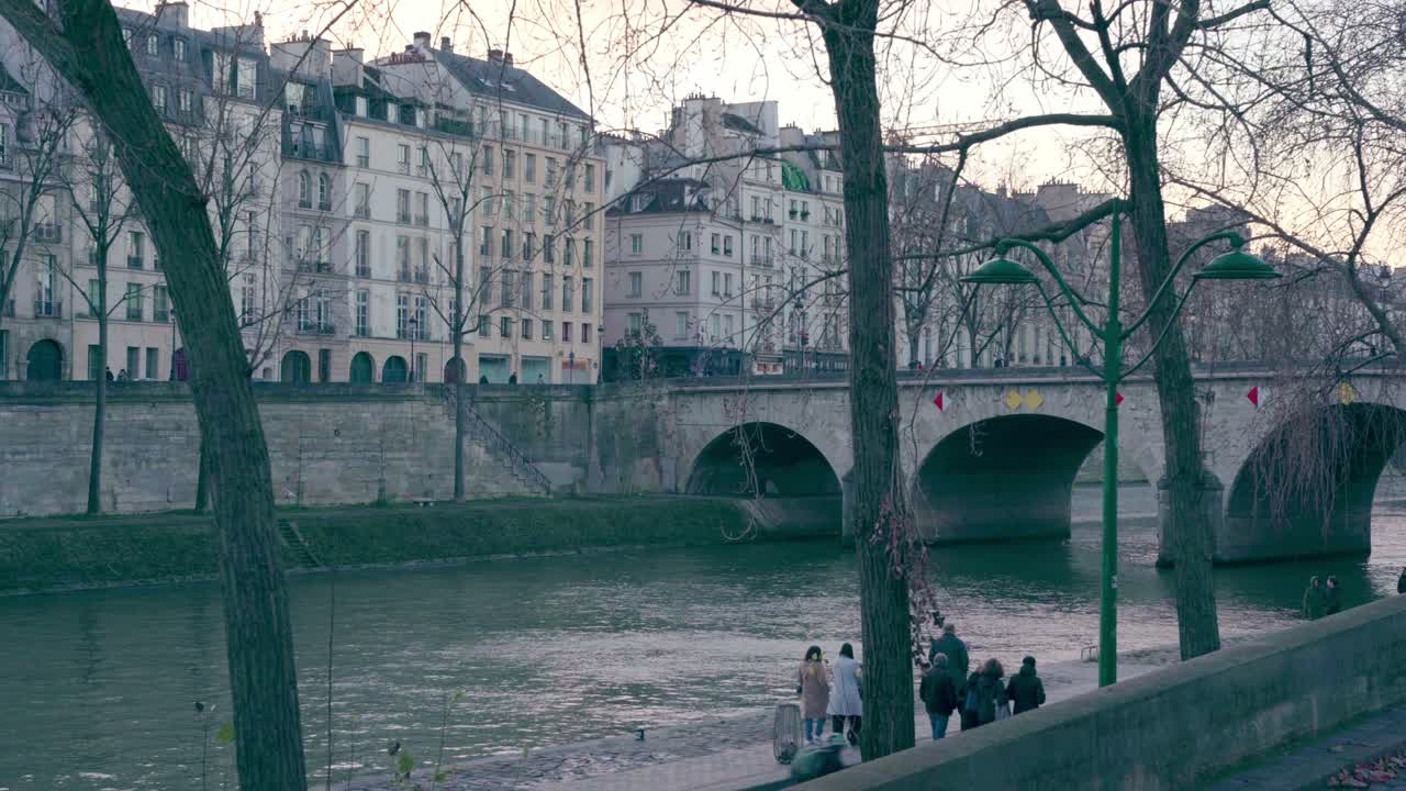 Family groups walking along the banks of the Seine River enjoying the sunset