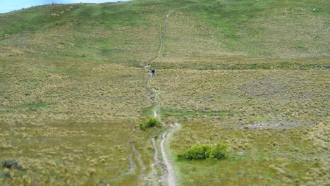Hikers-on-a-path-within-green-plains-in-windy-conditions