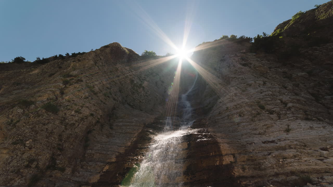 timelapse de la puesta del sol sobre una cascada de montaña que se inclina hacia abajo sunstar