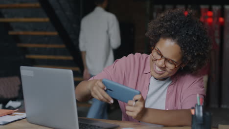 woman celebrating mobile game victory in office