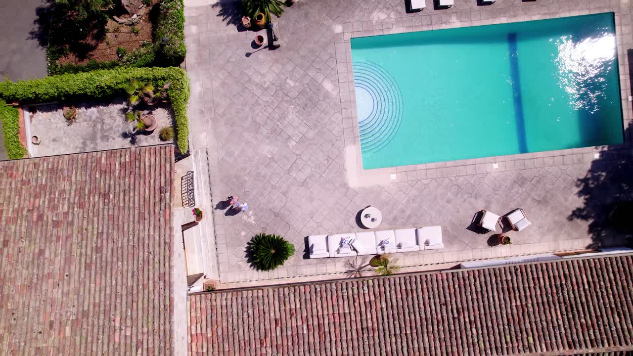 Top Shot View of Luxury Living: Two Persons Heading to the Poolside Oasis of a High-End Villa