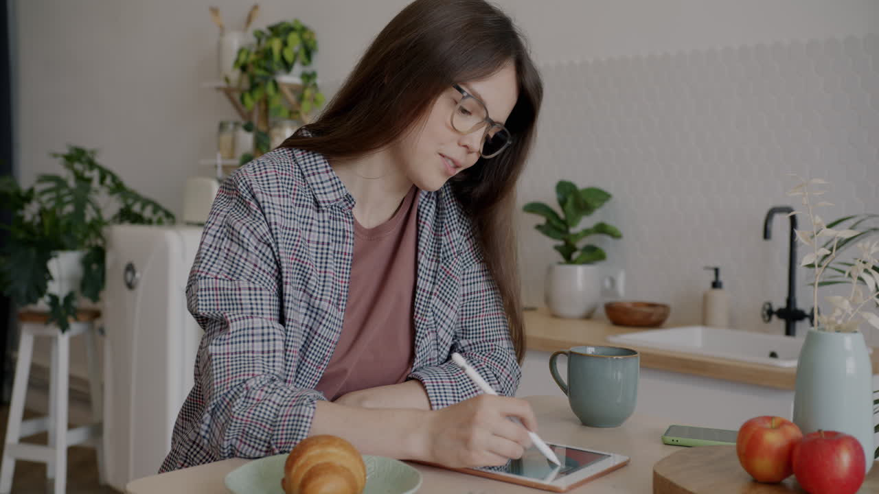 Woman Drawing on a Tablet in a Kitchen